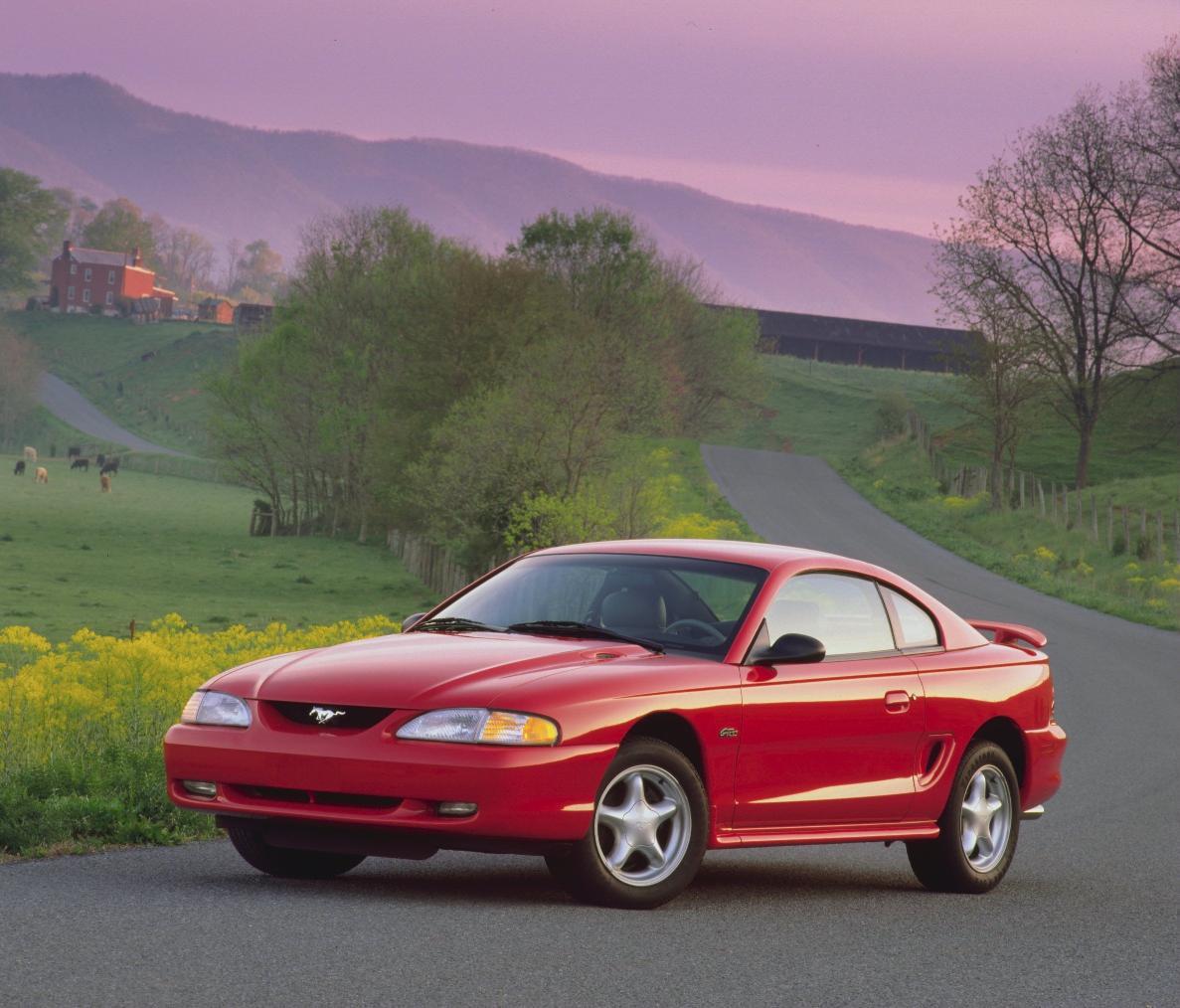 A red 1996 Ford Mustang GT (SN95) on a lonely road